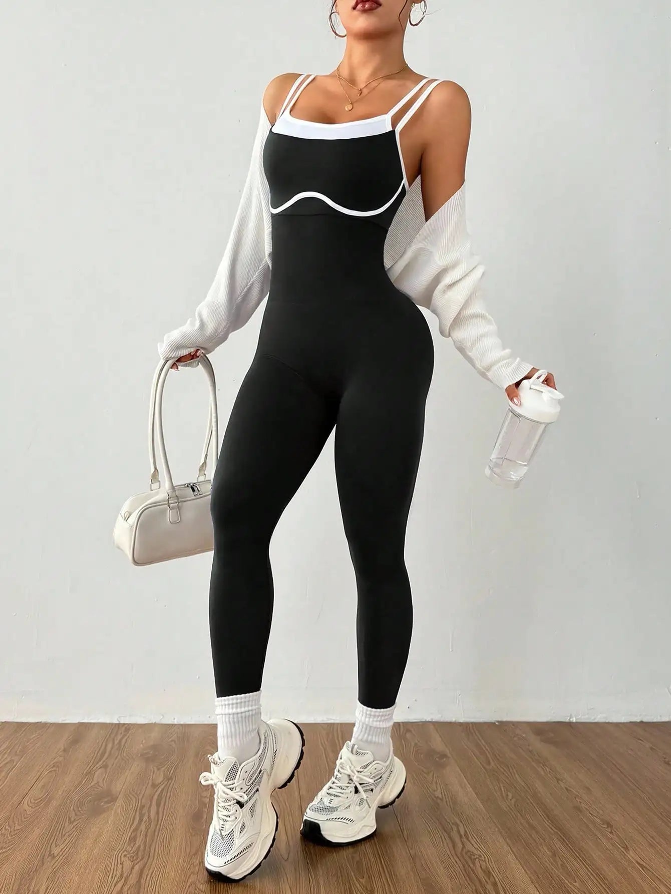 Combinaison sport fitness noire séchage rapide vue face sur femme portant un sac à main