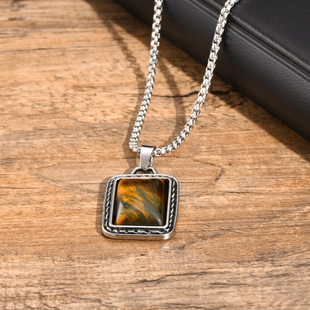 pendentif oeil de tigre homme pierre brune aux reflets dorés en gros plan sur bois