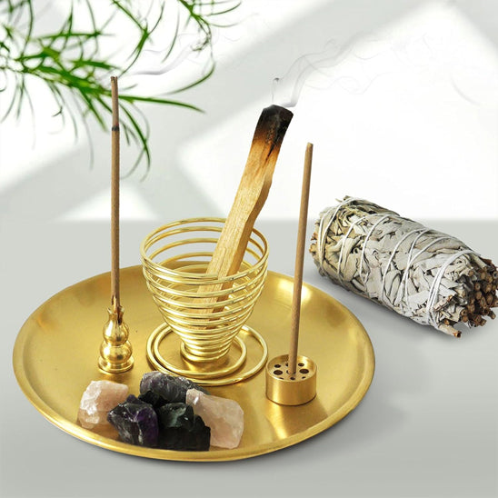 Plateau porte encens et récupérateur de cendre métal doré contenant 4 pierres brutes trois portes encens différents dans deux un bâton d'encens et un contenant un bâton de palo santo à côté un bâton se sauge
