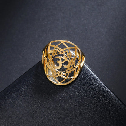 Bague chakra Couronne dorée avec symbole Om, présentée sur un support noir.
