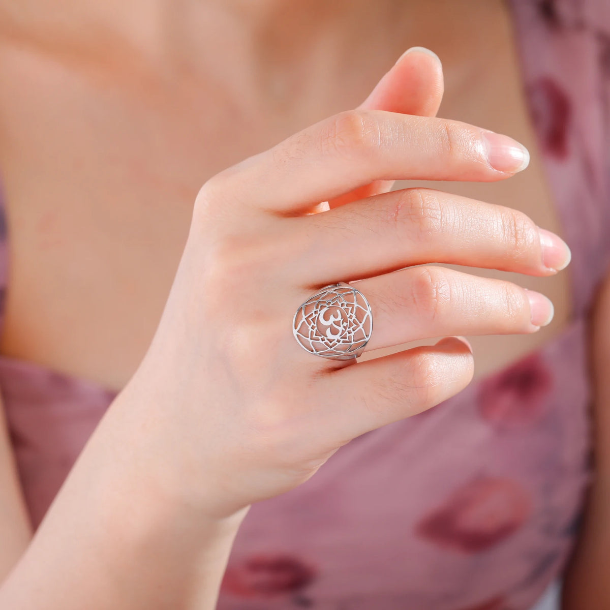 Bague chakra Couronne argentée avec motif ajouré et symbole Om, portée à l’annulaire.