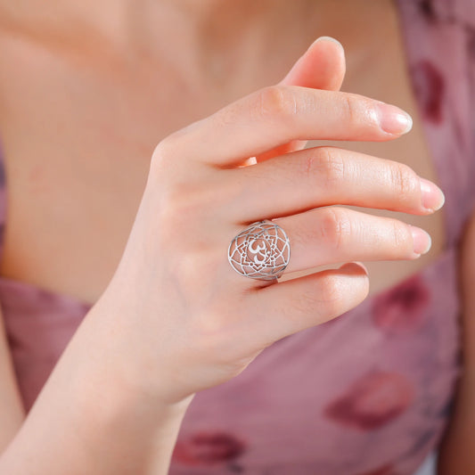 Bague chakra Couronne argentée avec motif ajouré et symbole Om, portée à l’annulaire.