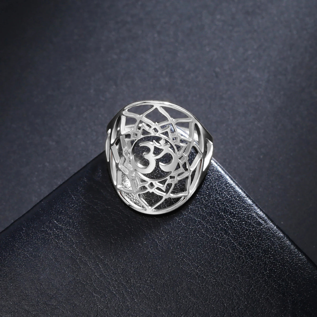 Bague chakra Couronne argentée avec symbole Om, présentée sur un support noir.