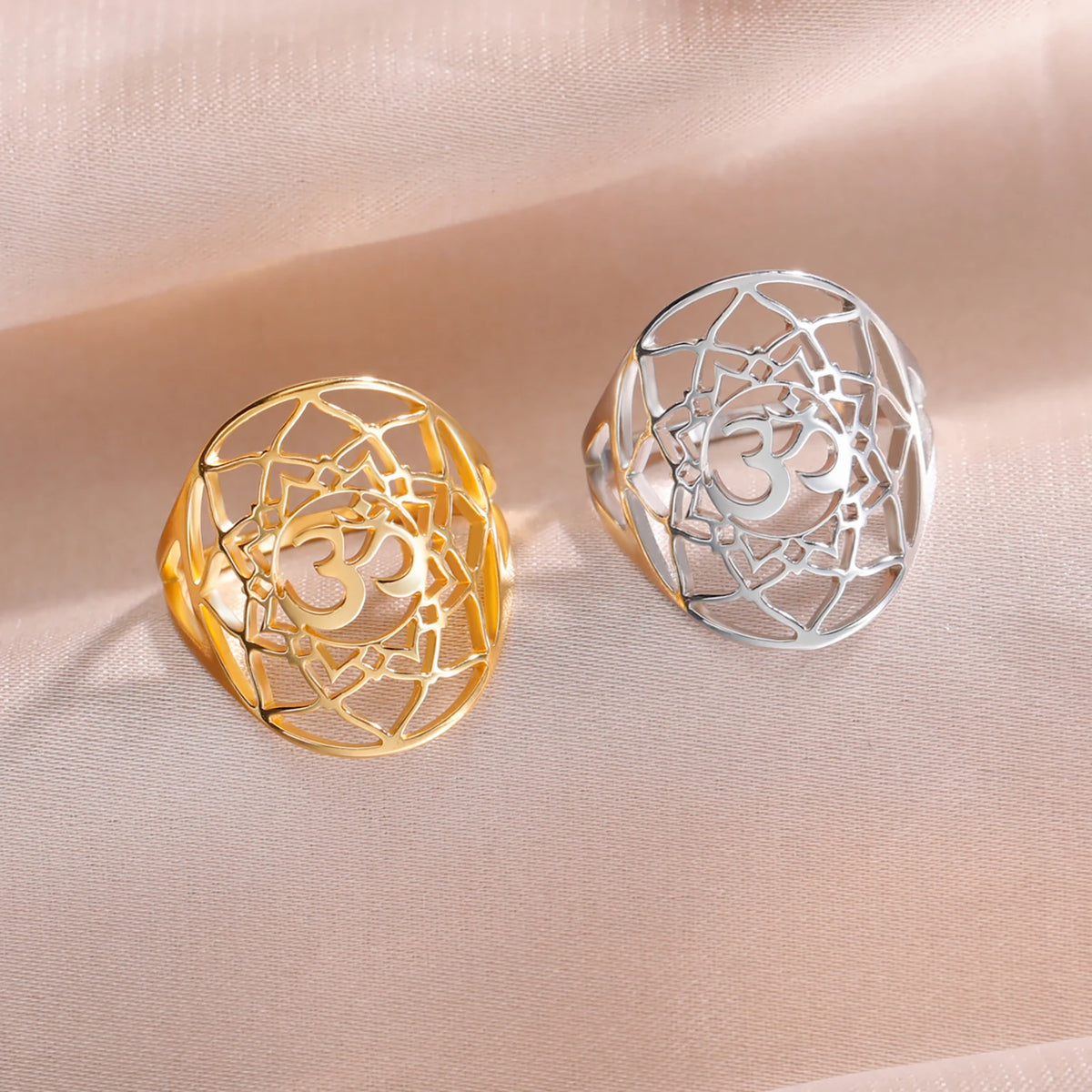 Bagues chakra Couronne dorée et argentée avec symbole Om, posées sur un tissu beige.