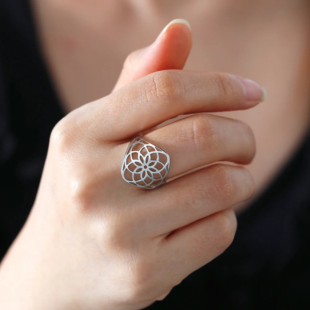 Bague fleur de vie argentée au motif ajouré, portée au doigt d’une femme