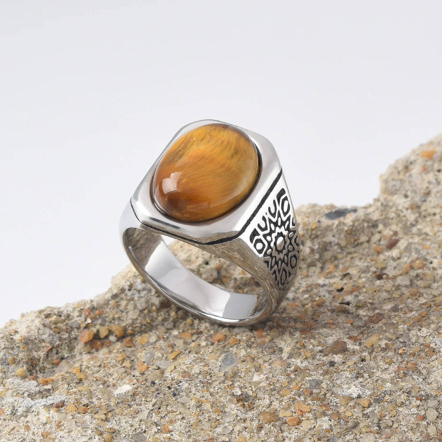Bague oeil de tigre homme en acier inoxydable 316L posée sur une pierre naturelle