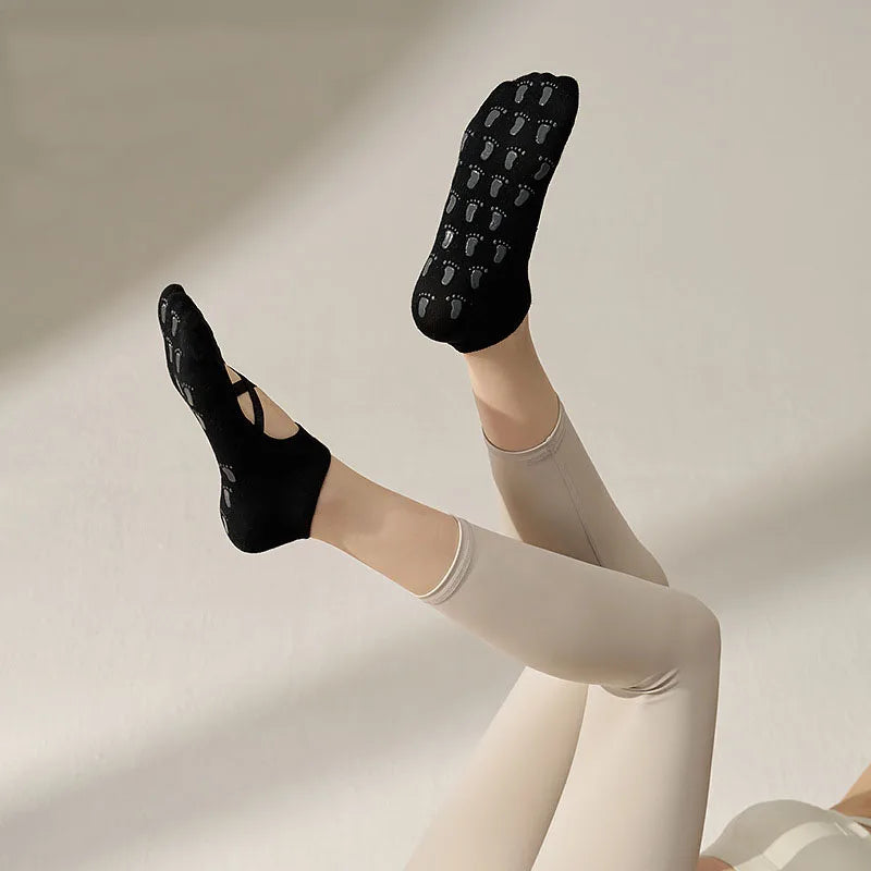 Chaussettes antidérapantes yoga noires lanières croisées pieds en l'air