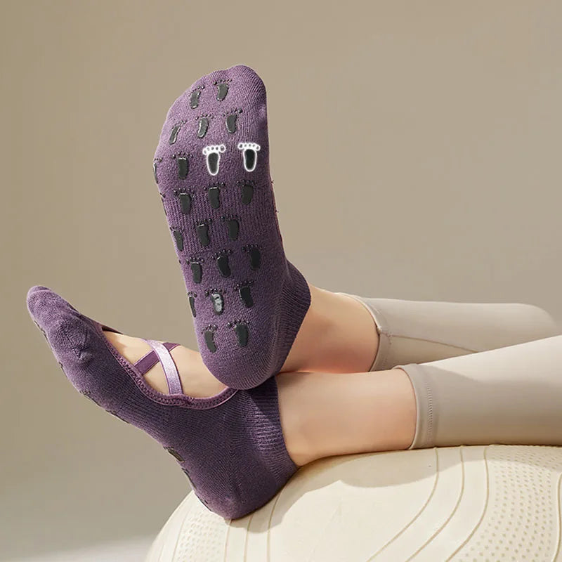 Chaussettes antidérapantes yoga violettes portées sur pieds croisés dessus lanières dessous silicones en forme de pieds 