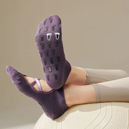 Chaussettes antidérapantes yoga violettes portées sur pieds croisés dessus lanières dessous silicones en forme de pieds 