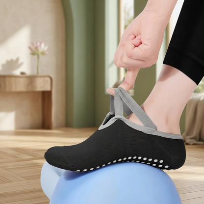 Gros plan sur les sangles grises élastiques des chaussettes de yoga, portées sur un ballon bleu.