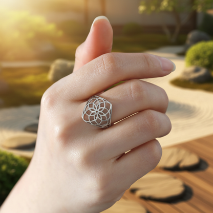 Bague anti stress fleur de vie argentée portée au doigt fond ensoleillé