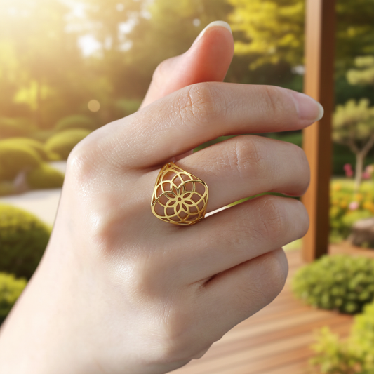 Bague anti stress fleur de vie dorée portée au doigt fond ensoleillé