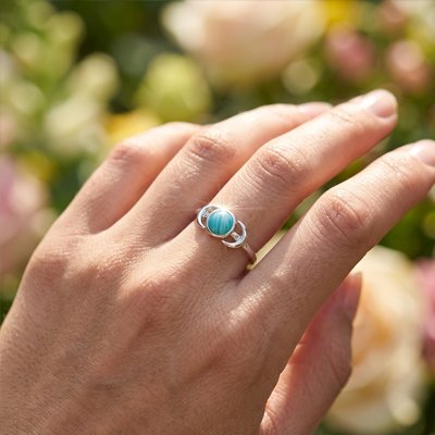 Bague femme sertie d'une turquoise qui brille au soleil fond fleur