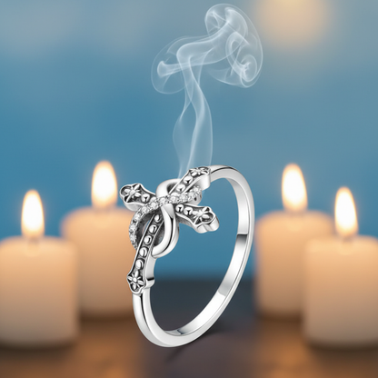 Gros plan bague symbolique croix infinie argent 925 zircons, fond bleu ciel et lumière bougies