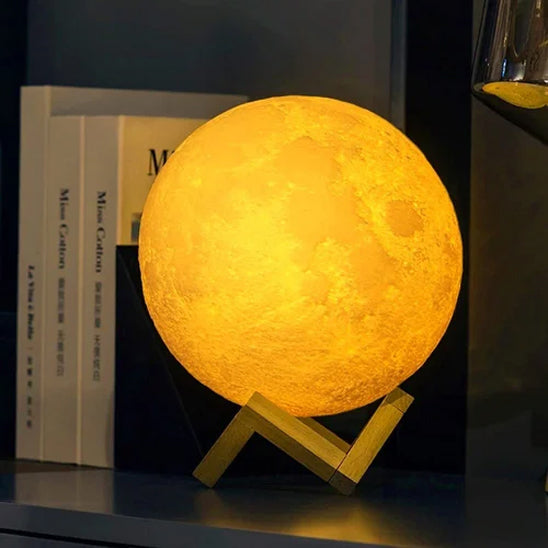 lampe en forme de lune lumière jaune socle en bois sur étagère près de livres