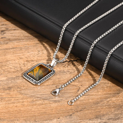 pendentif oeil de tigre homme présenté avec sa chaîne argentée et son fermoir sur une table en bois