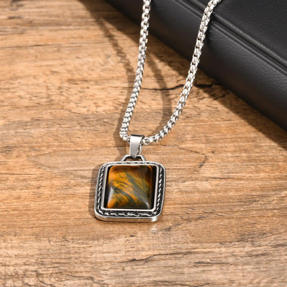 pendentif oeil de tigre homme pierre brune aux reflets dorés en gros plan sur bois 